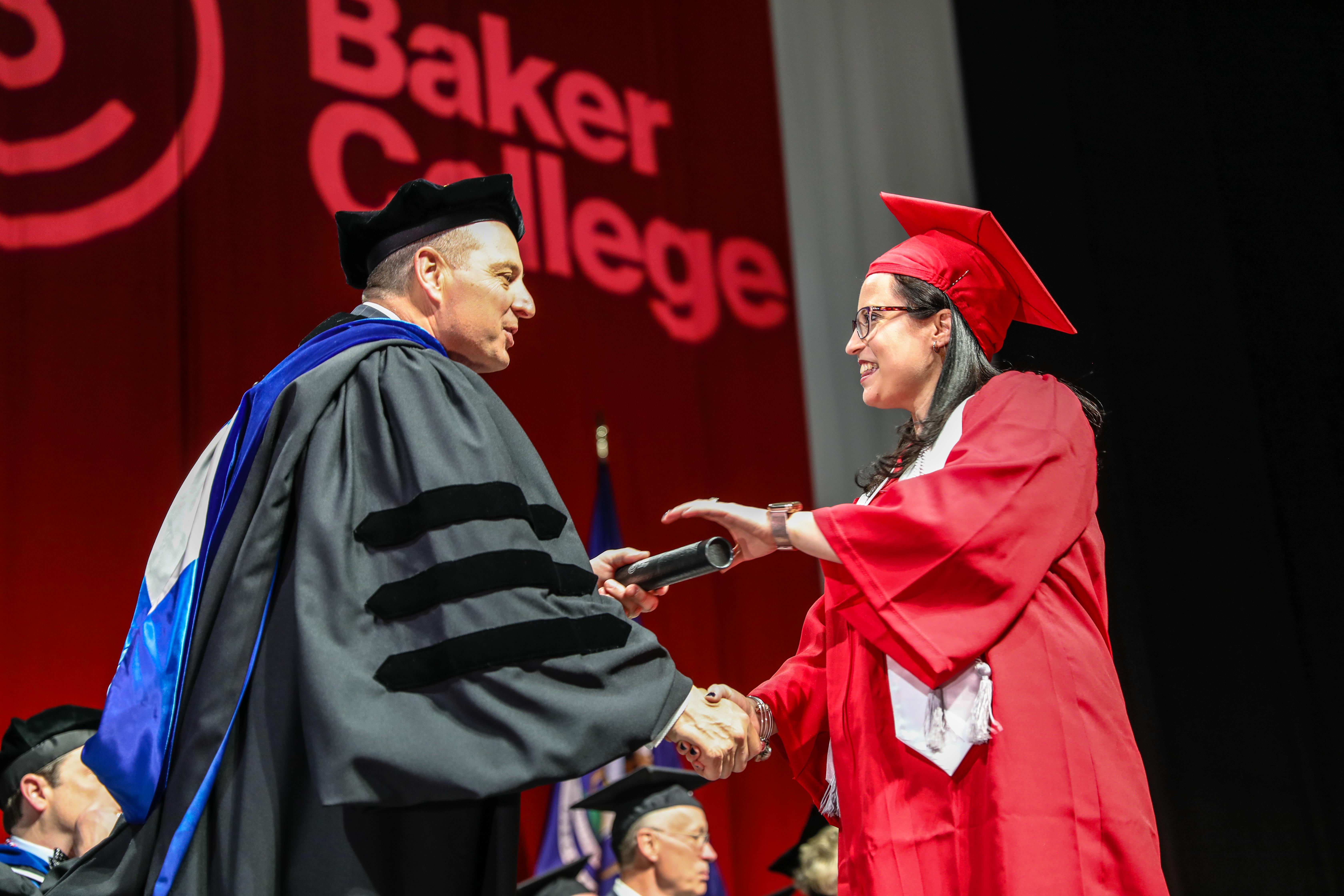 President Bart Diag hands a graduation scroll to a graduate.