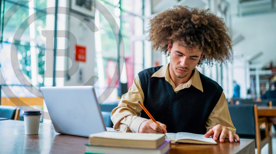 Student takes notes next to their open laptop on campus.