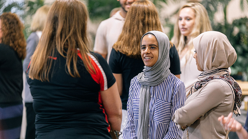 Young student and her mother speakng to a Baker College Staff member at an event.