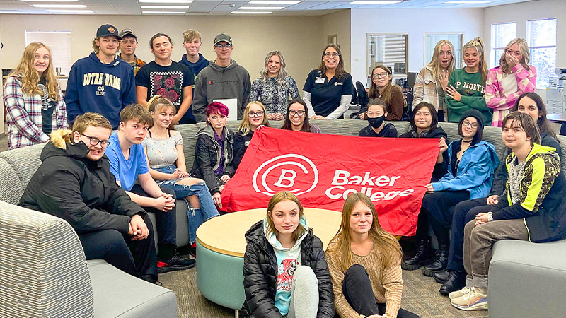 Group of high school students pose with Baker College flag