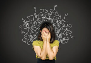 Woman with her head in her hands surrounded by illustrations of stress.