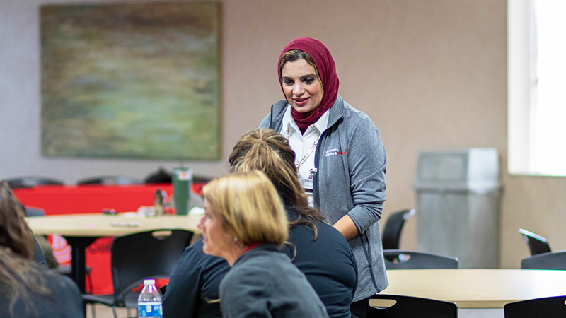Dr. Walaa Awad speaking with staff members at a DEIJ event.