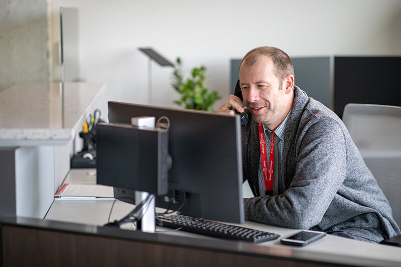 A man on the phone next to his computer.