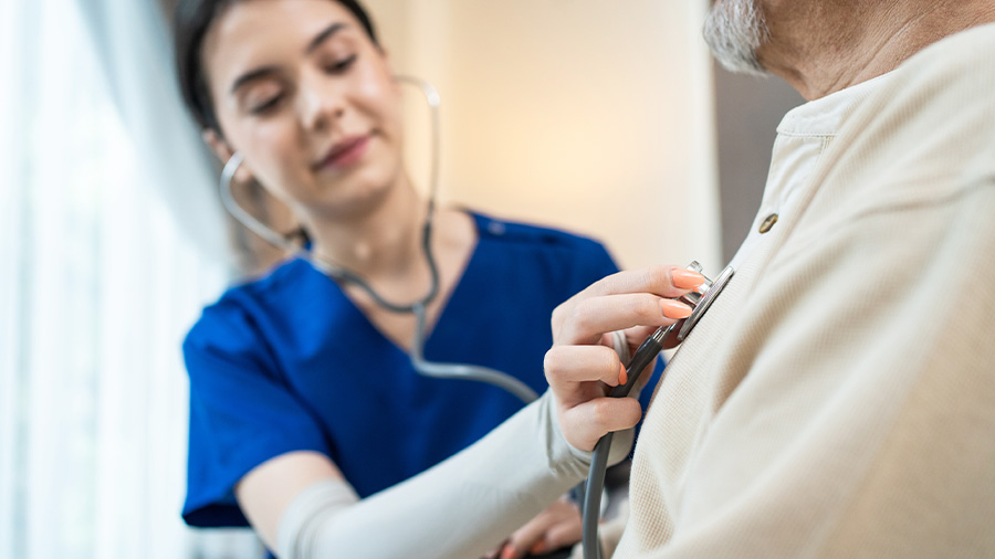 Young woman holding a stethoscope to an older man's chest